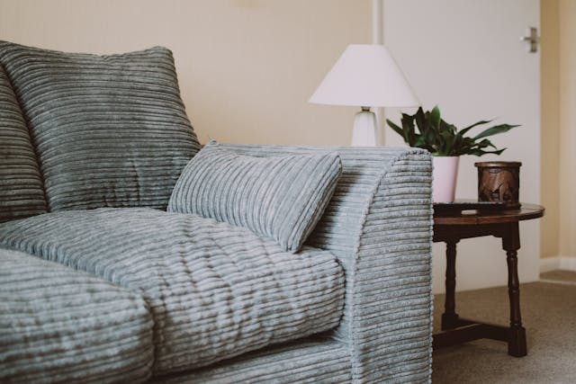 A grey couch with a small wooden side table next to it